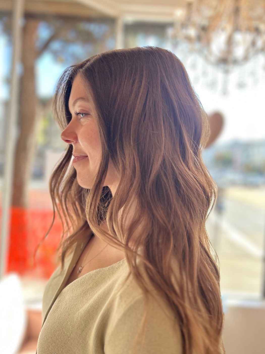 Profile of a woman with long wavy auburn hair with dimensions.