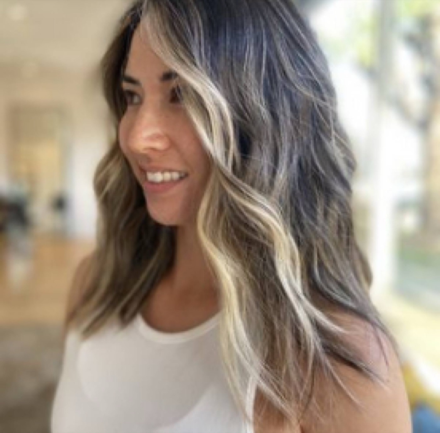 Smiling client with dimensional brunette hair and face-framing blonde highlights